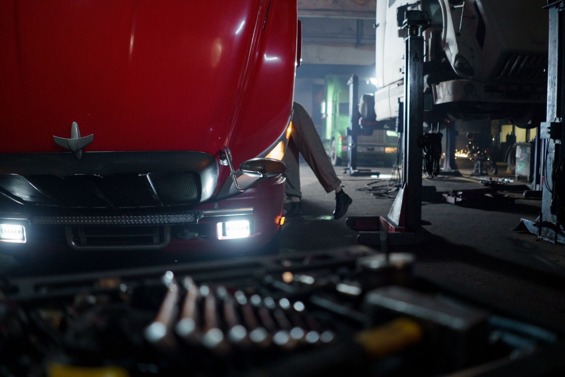 Diesel technician working on the front end of a semi truck with a tool tray in the foreground